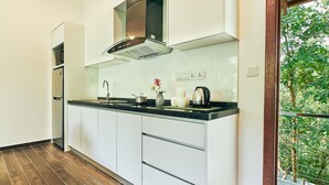 A modern kitchen with white cabinets, a stainless steel range hood, and a black countertop. - Ranis Lodge (Langkawi)