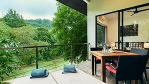 A balcony with a table and chairs, overlooking a lush green landscape. - Ranis Lodge (Langkawi)