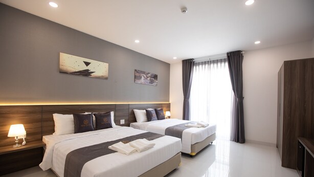 A modern hotel room with two beds, a large window with curtains, a wooden headboard, and a wall-mounted artwork. - Hera Hotel (Ho Chi Minh City)