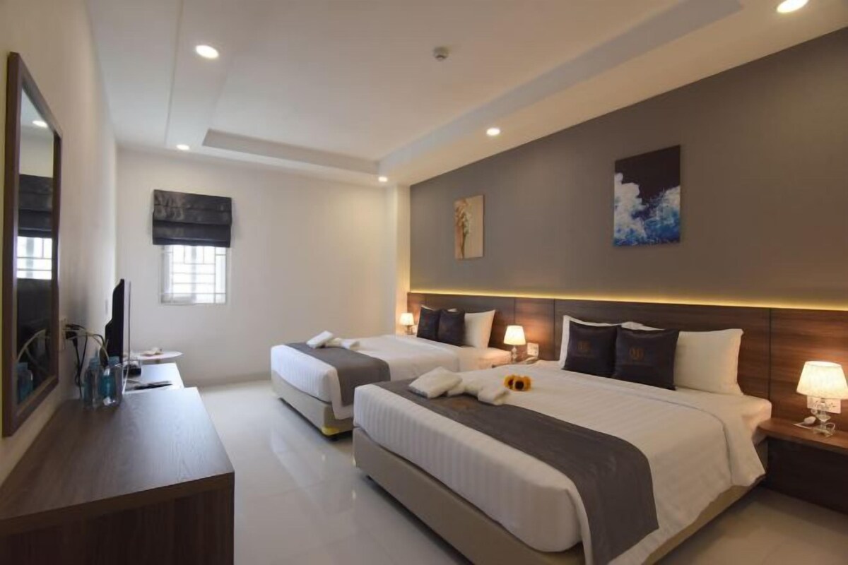 Une chambre d’hôtel avec deux lits, un bureau et un grand miroir.