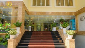 A hotel entrance with a marble staircase, potted plants, and a reception desk. - Hera Hotel (Ho Chi Minh City)