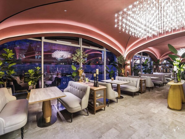 Un intérieur moderne avec des arches courbes au plafond, des espaces de détente et une grande fenêtre offrant une vue sur le paysage urbain.