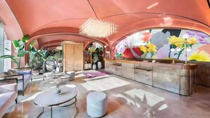 Eine moderne Lobby mit gewölbter Decke, einer Rezeption und einer großen Blumenwand.