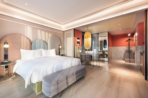 Camera d'hotel moderna con un letto grande, una scrivania e un bagno con specchio e lavabo.