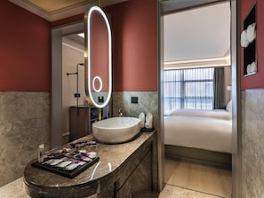 Une salle de bain moderne avec un comptoir en marbre, un grand miroir doté d’un éclairage intégré, un lavabo et un meuble-vasque.
