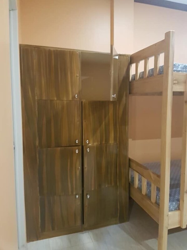 Una habitación con un armario de madera y una cama litera.