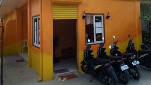 A building with a yellow and orange exterior, a covered entrance, and several parked motorcycles. - Stella'z Guesthouse (San Juan)