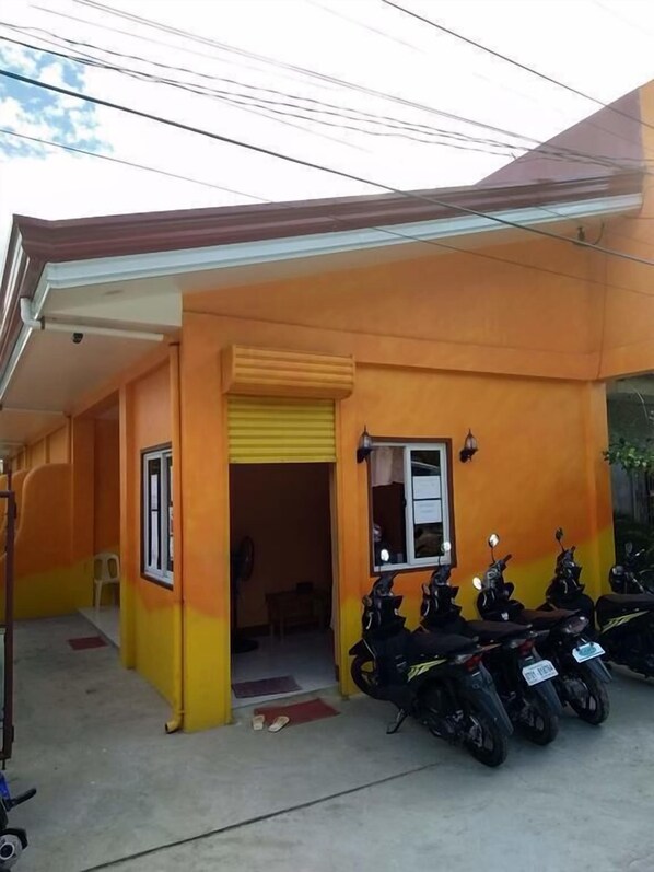 A building with a yellow and orange exterior, a covered entrance, and several parked motorcycles. - Stella'z Guesthouse (San Juan)