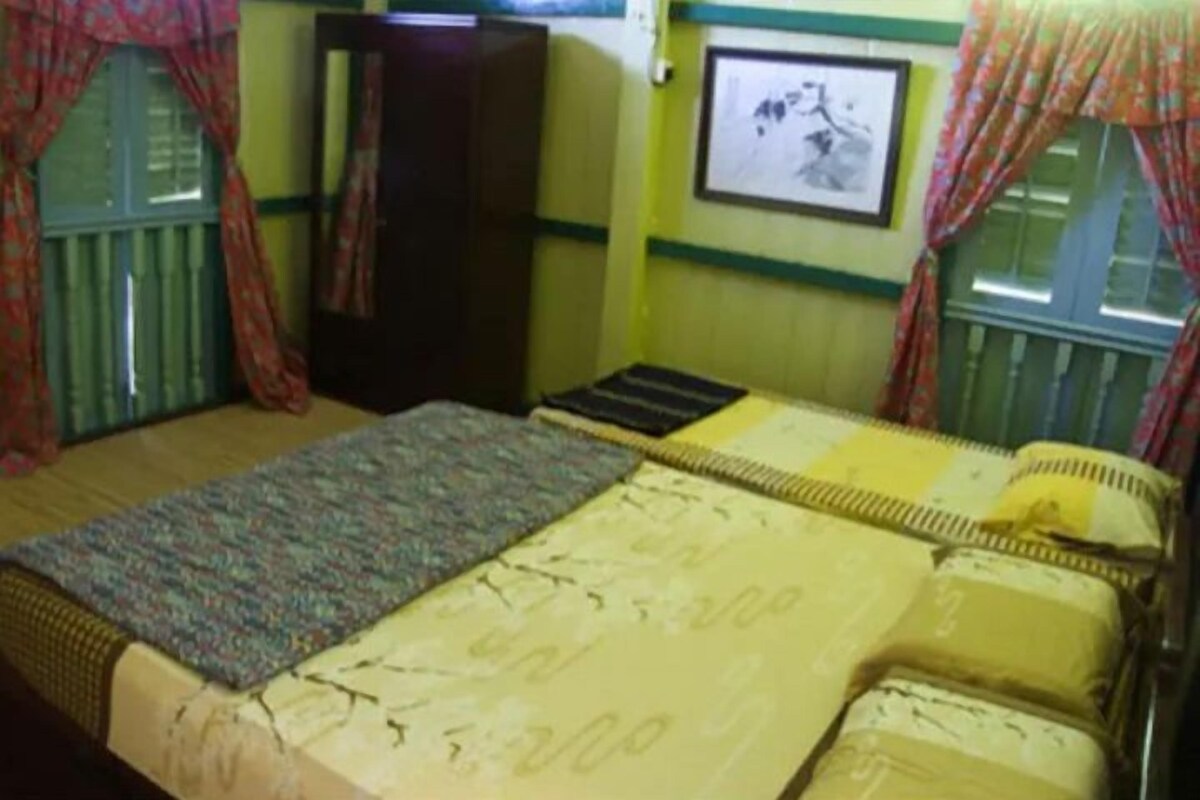 A room with a bed, a small table, and a window with curtains.