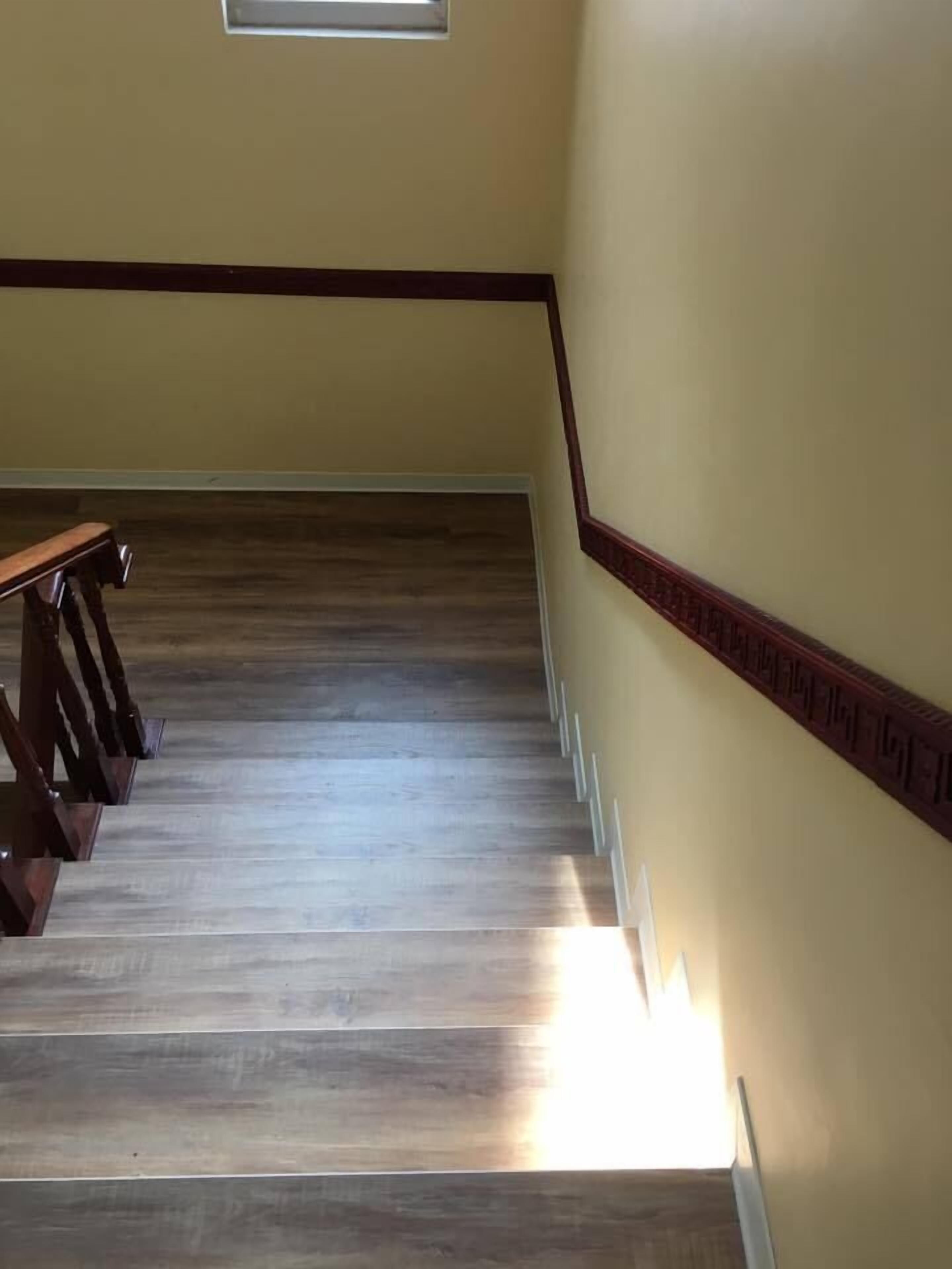 A wooden staircase with a handrail and a light fixture at the bottom.