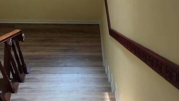 A wooden staircase with a handrail and a light fixture at the bottom.