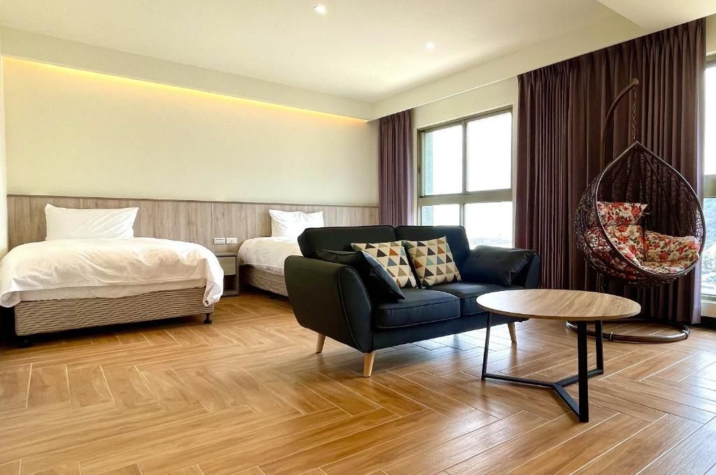A hotel room with a bed, a sofa, a hanging chair, and a small table.