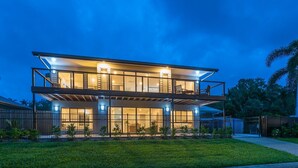 Een modern huis met twee verdiepingen, een balkon, grote ramen en een verzorgd gazon.