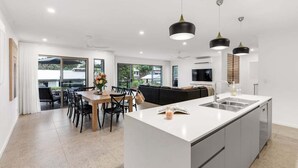 Een moderne keuken met een centraal eiland, een eethoek met stoelen en hanglampen.