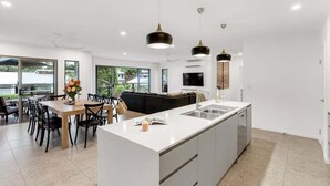 Een moderne keuken met een centraal eiland, hanglampen en een eethoek met uitzicht.