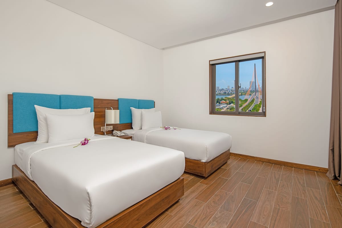 A hotel room with two beds, a city view, and a wooden floor.