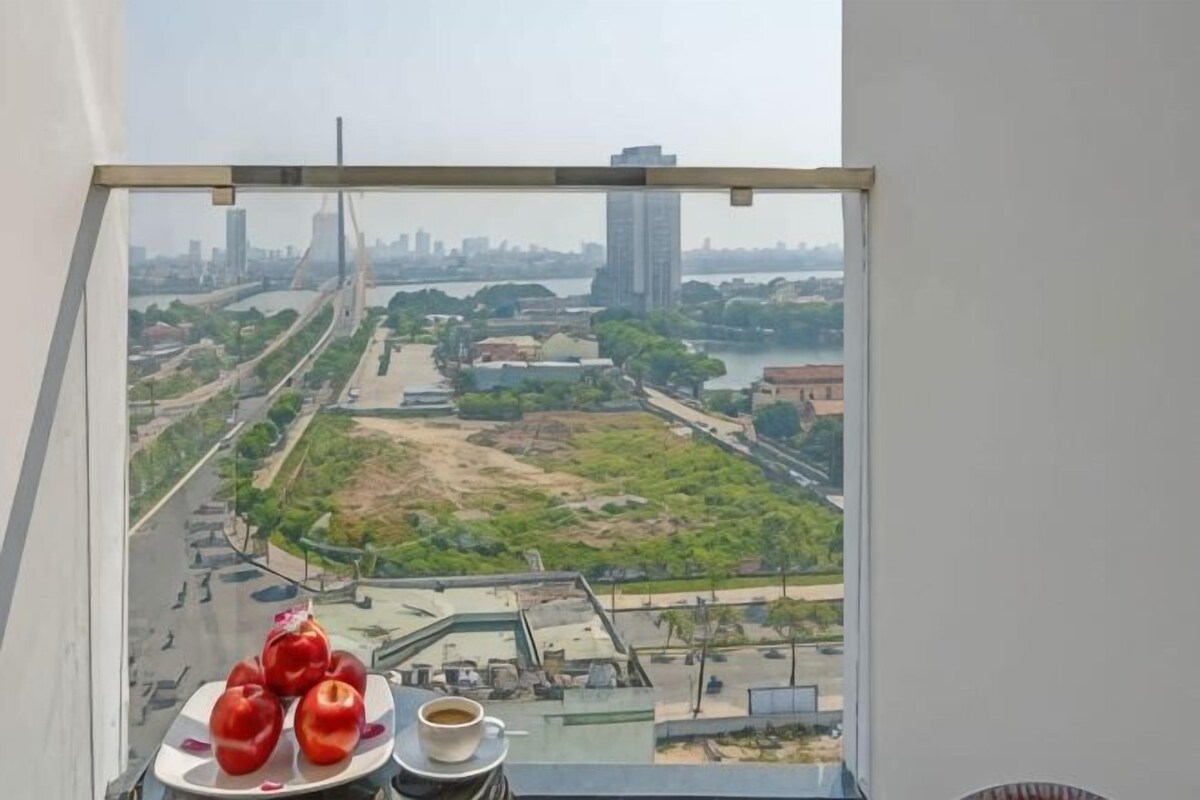 Vista da janela com uma paisagem urbana, incluindo uma ponte, edifícios e um rio.