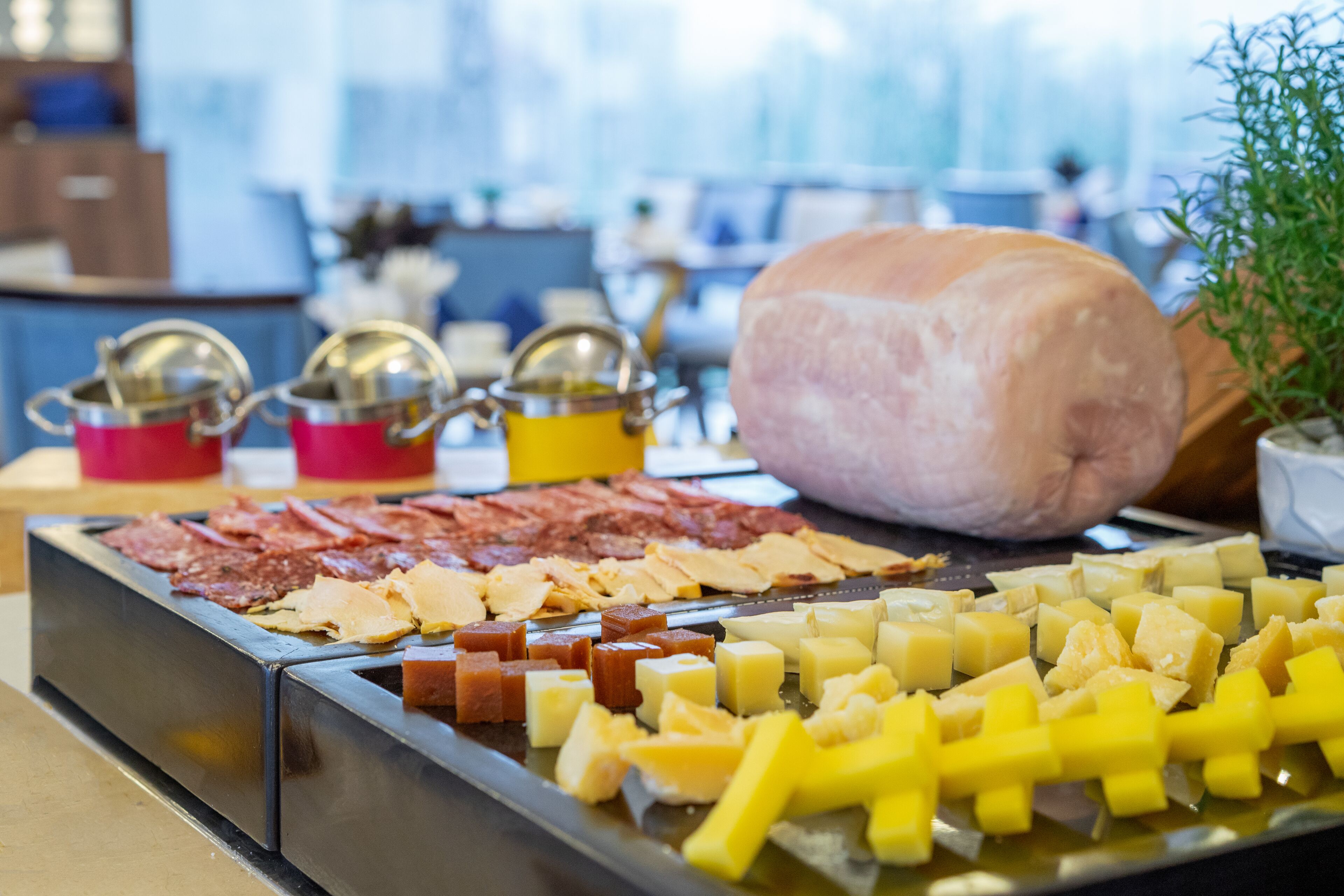 A buffet with various cheeses, meats, and a large loaf of bread.