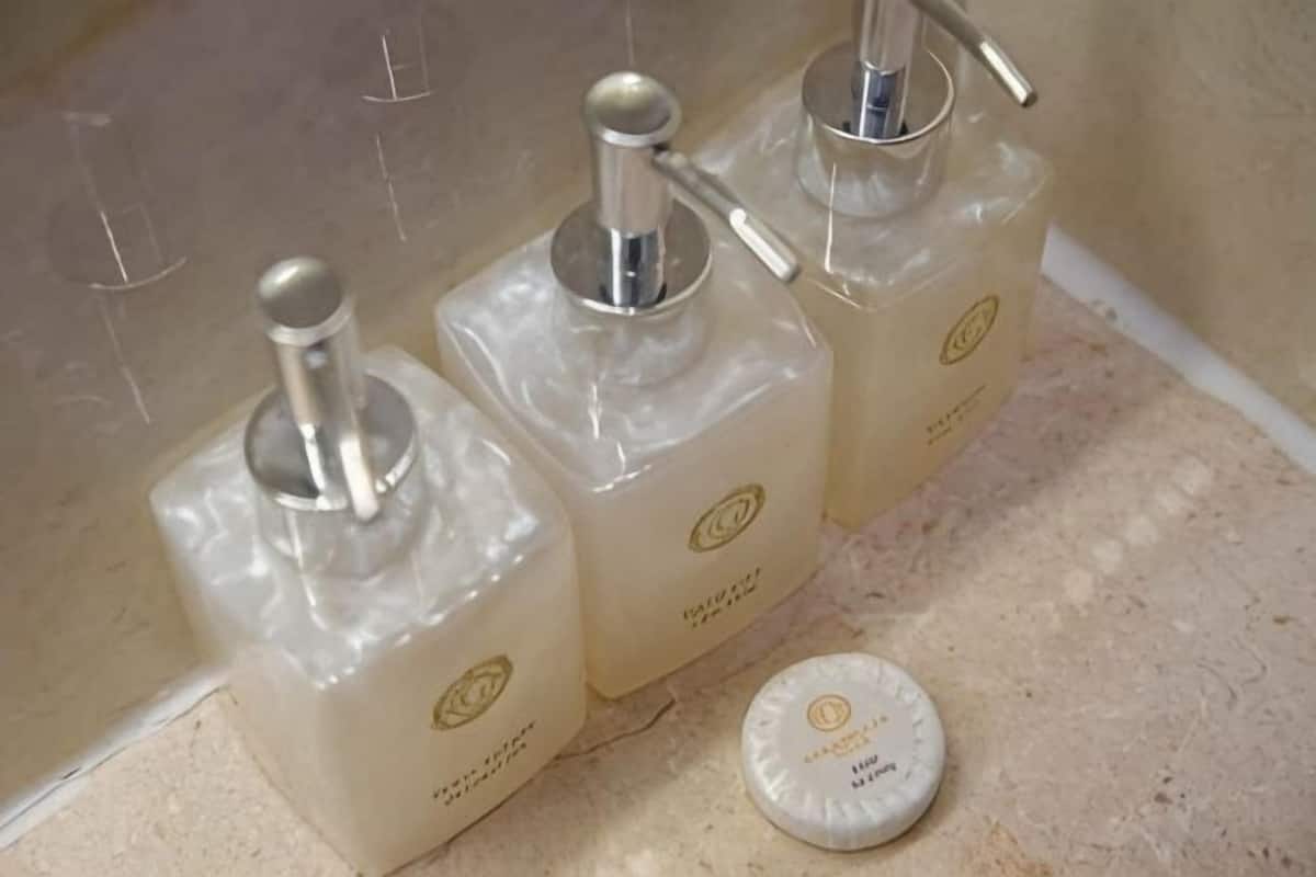 Three transparent bottles with metal tops and a white cap on a countertop.