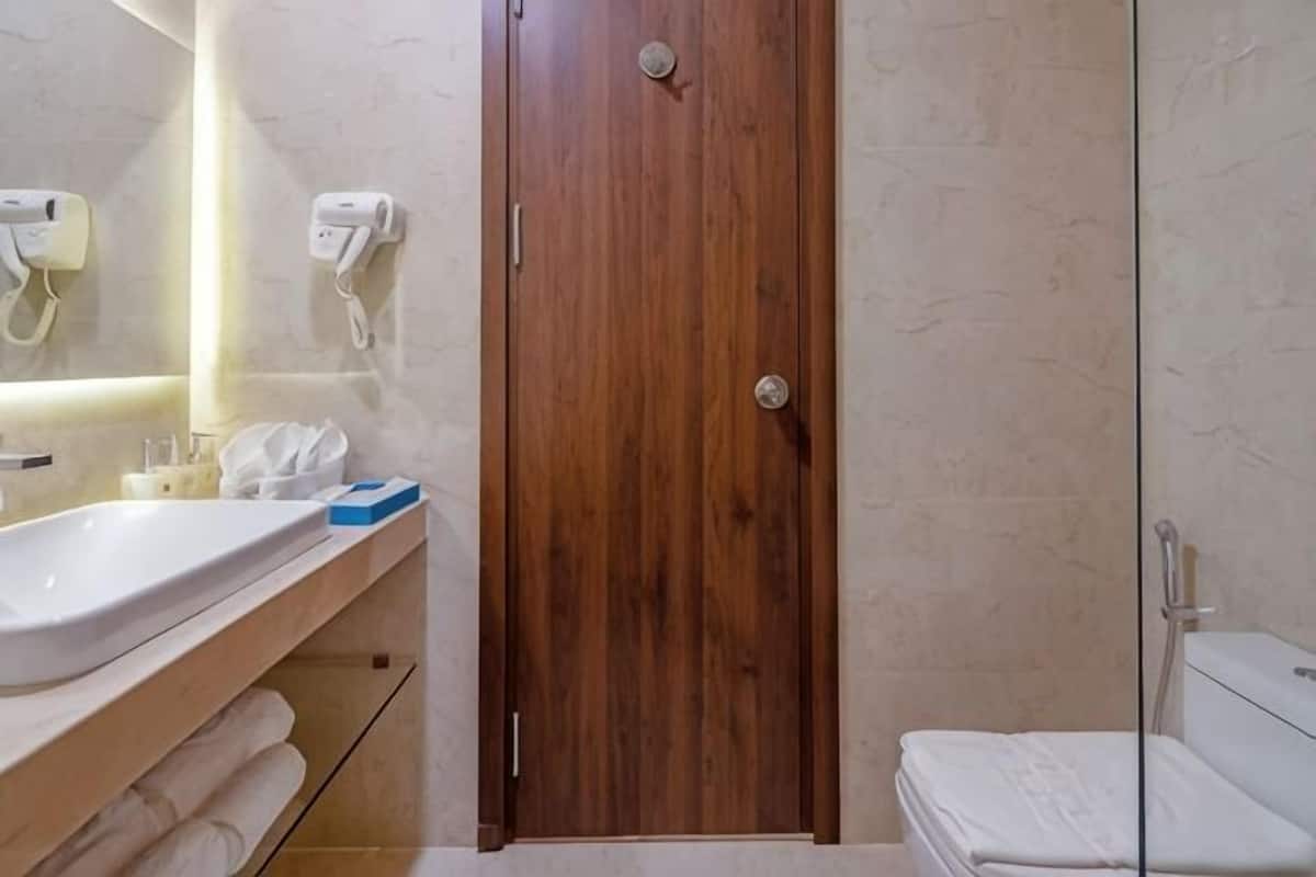 A bathroom with a wooden door, a white sink, and a glass shower enclosure.