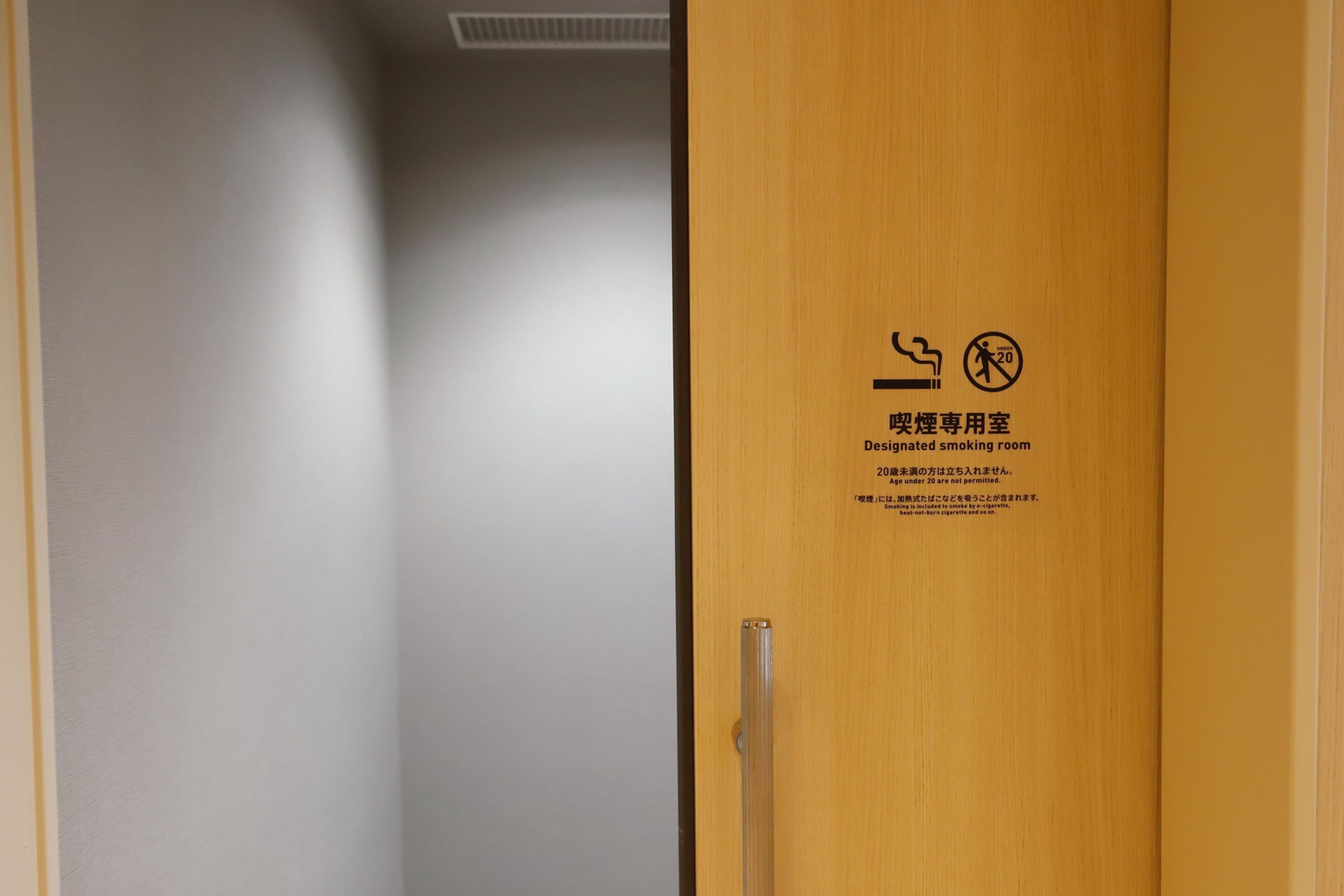 A door with a sign indicating a designated smoking room and a 20-meter no-smoking zone.