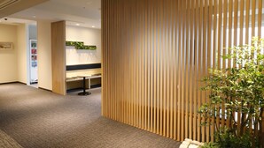A modern interior with a wooden partition, a reception desk, and a plant. - Keikyu EX INN Haneda Innovation City (Tokyo)