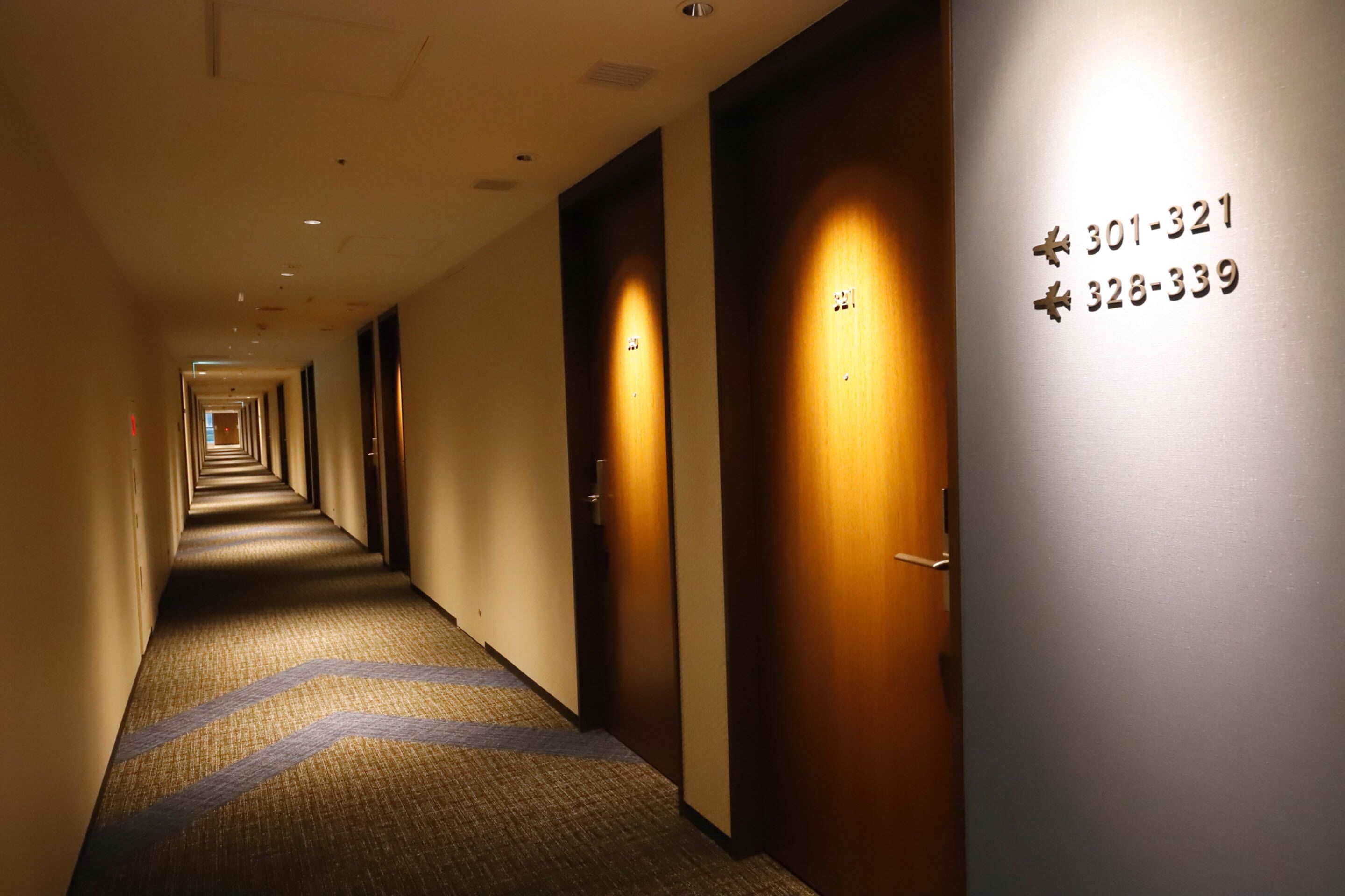 A hotel hallway with doors marked with phone numbers.