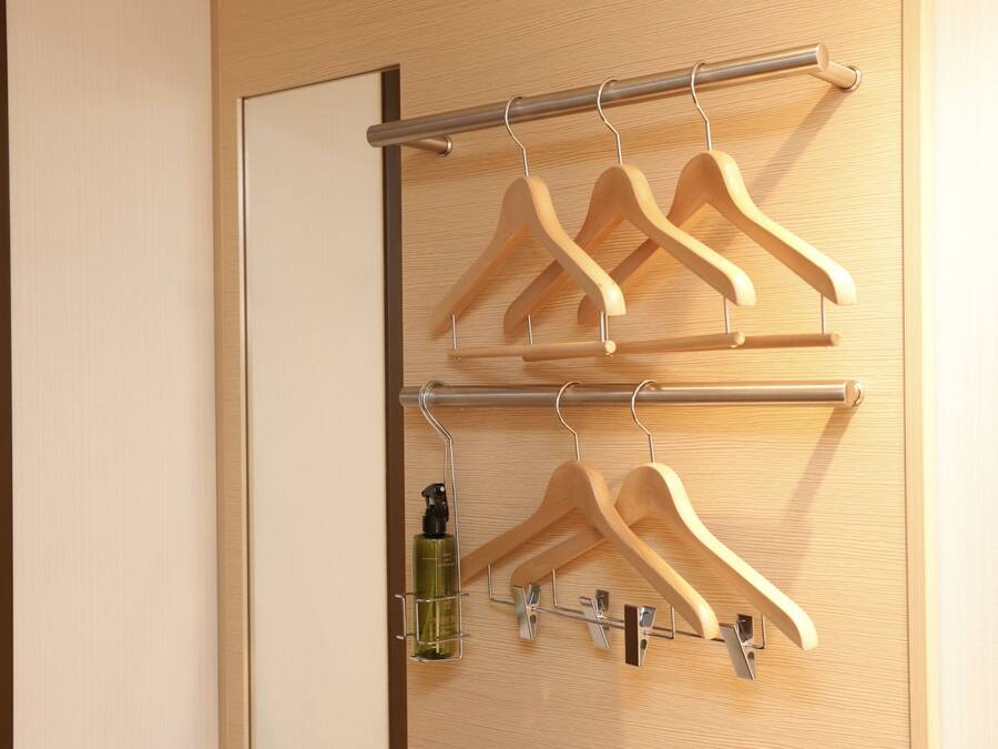A wooden door with a metal rack holding wooden hangers and a bottle of hand sanitizer.