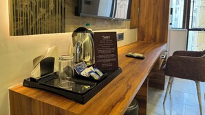 Mostrador de recepción de hotel con una máquina de café, un vaso y una bandeja con artículos de aseo.
