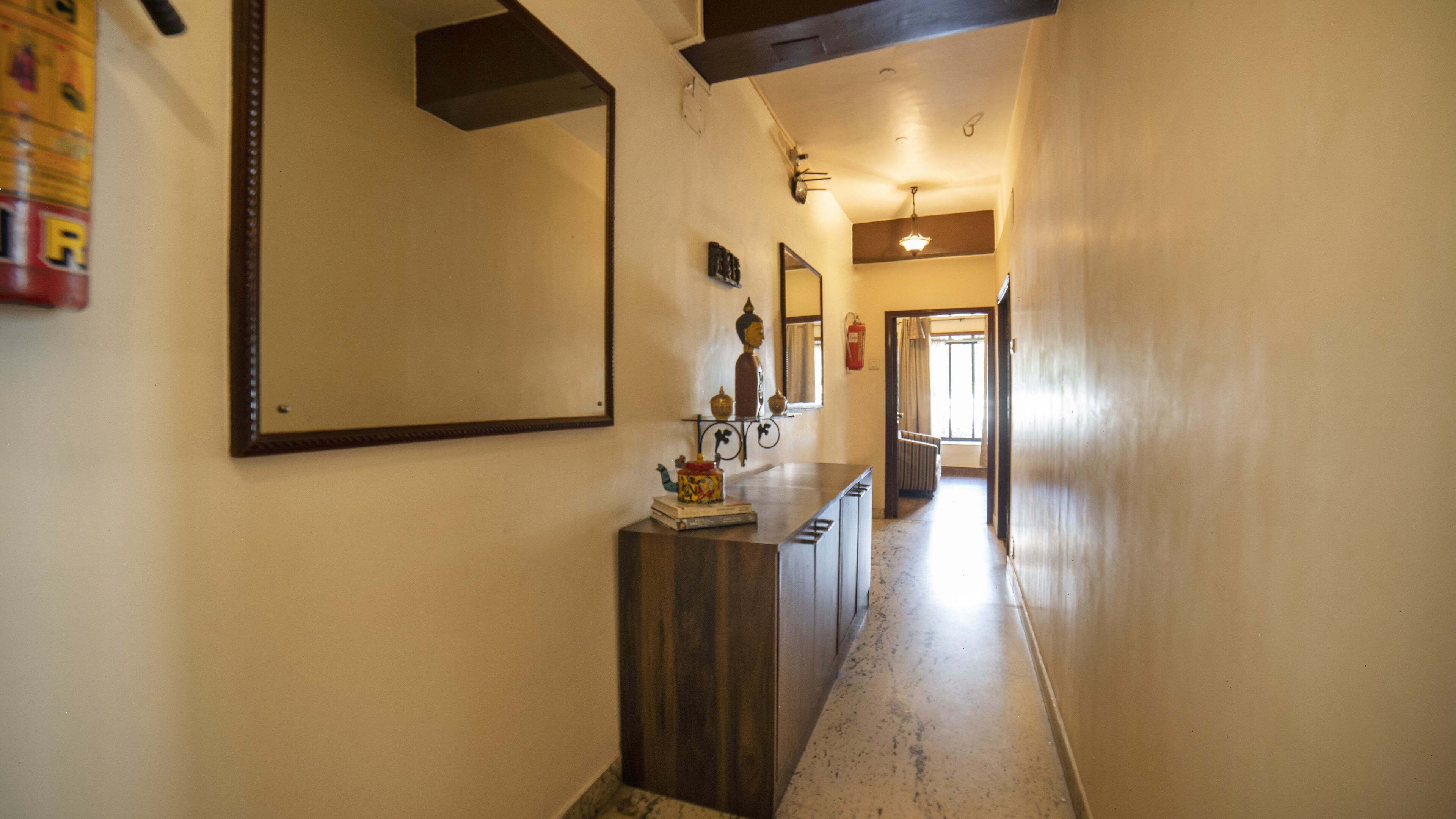 A hallway with a wooden counter, a Buddha statue, and a mirror on the wall.