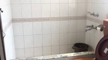 Un baño con ducha, inodoro y cubo de basura.
