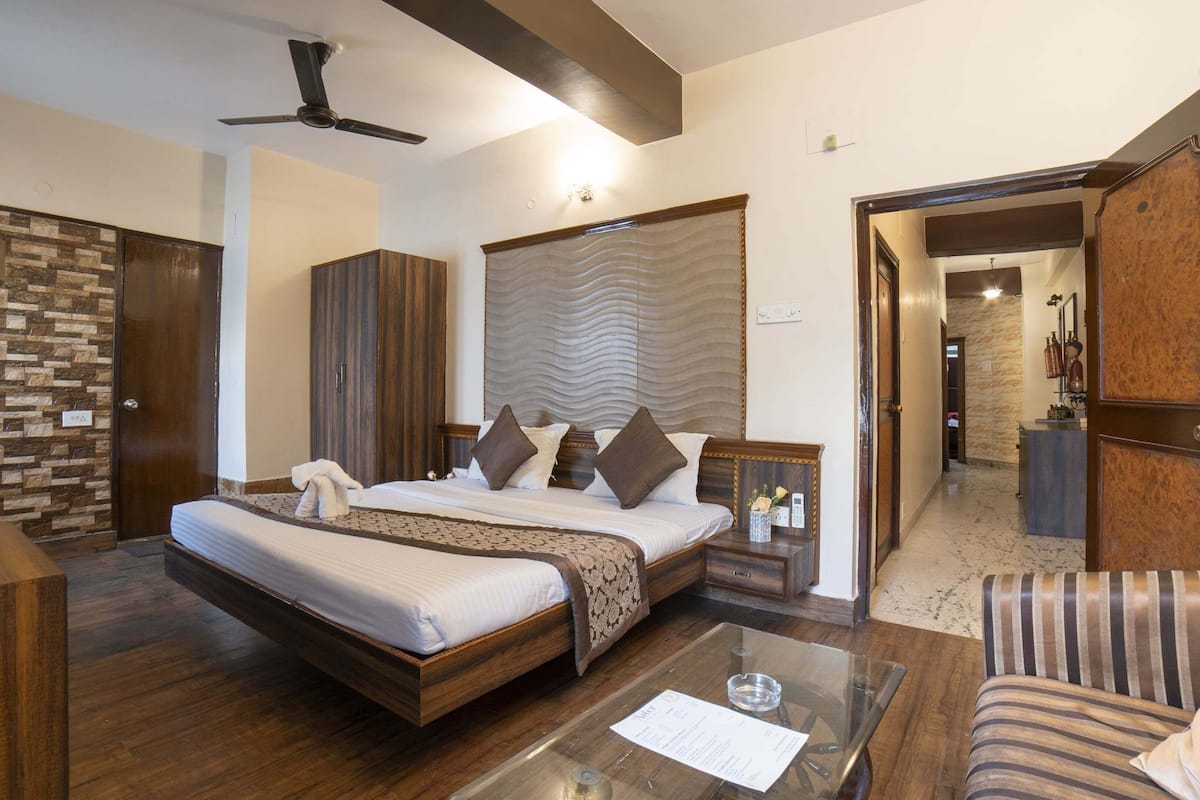 Habitación de hotel con cama, escritorio, silla, mesa de centro de vidrio y armario.