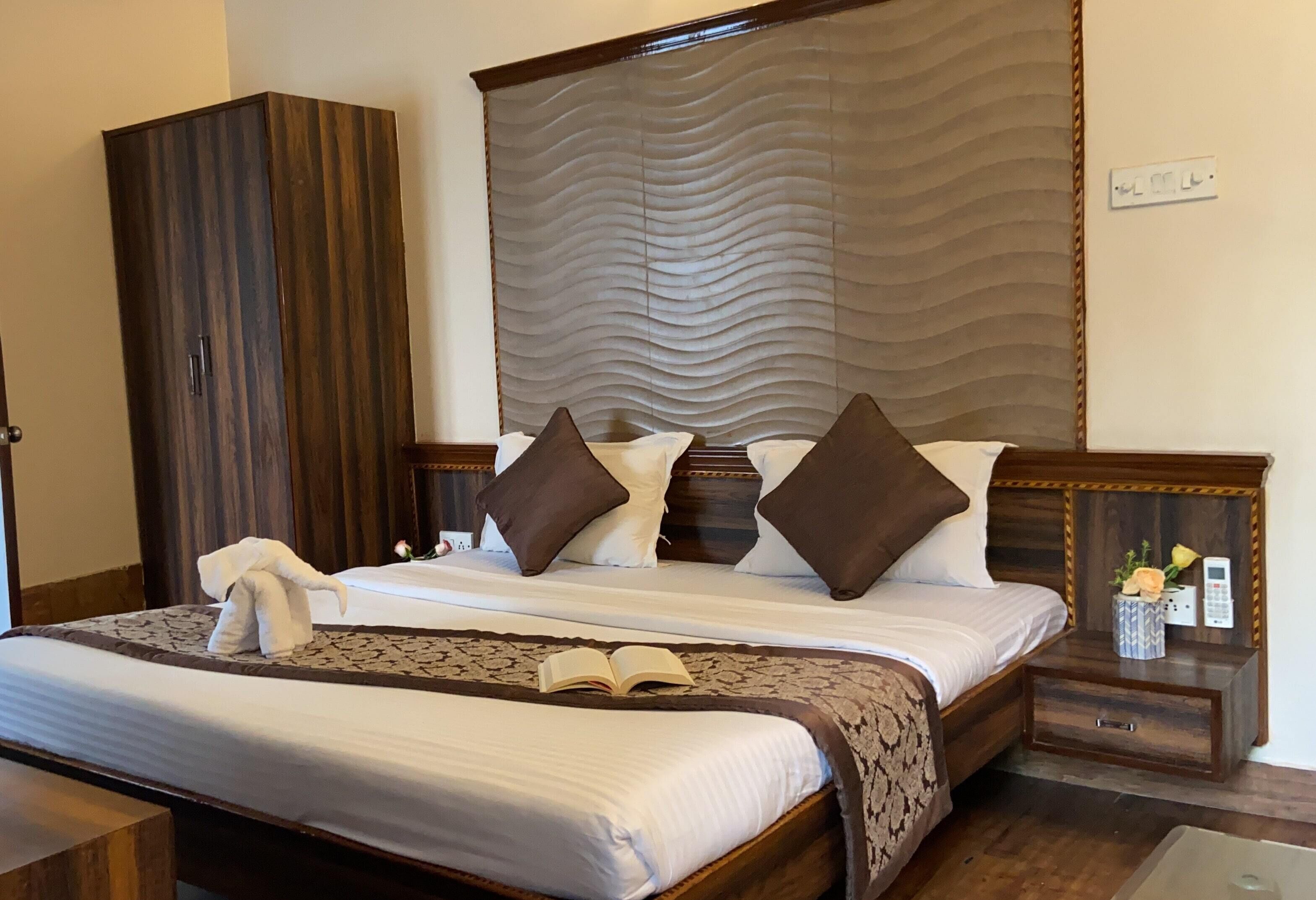 A neatly made bed with a patterned bedspread, a bedside table with a vase of flowers, and a wardrobe.