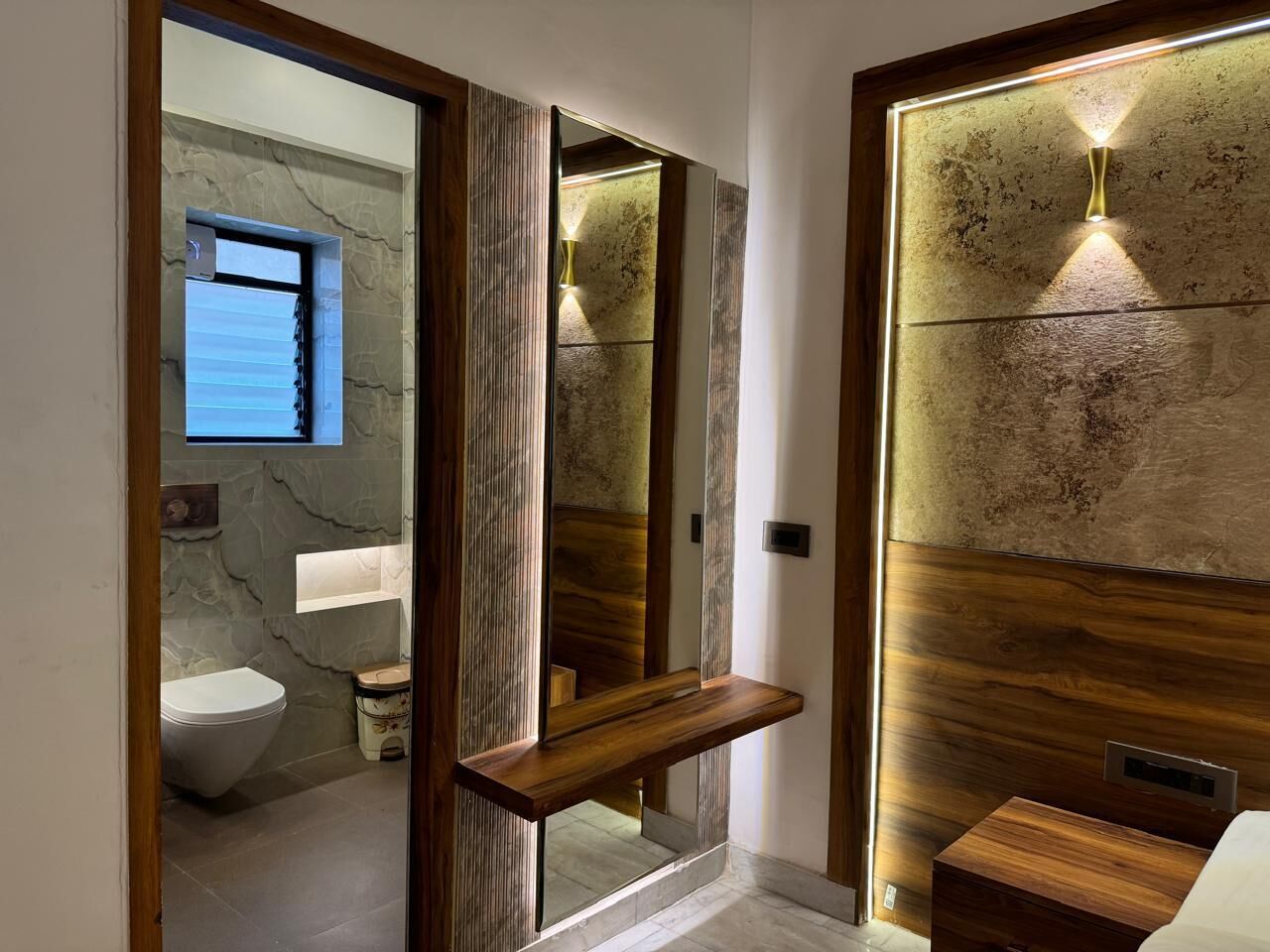 A modern bathroom with a wooden vanity, a mirror, and a toilet.