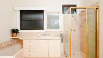 A modern bathroom with a bathtub, a glass-enclosed shower, and a vanity with drawers.