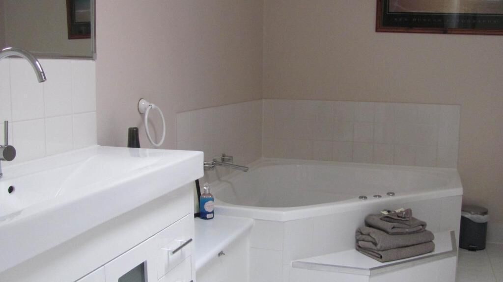 Un baño moderno con un lavamanos blanco, una bañera grande y un perchero para toallas.