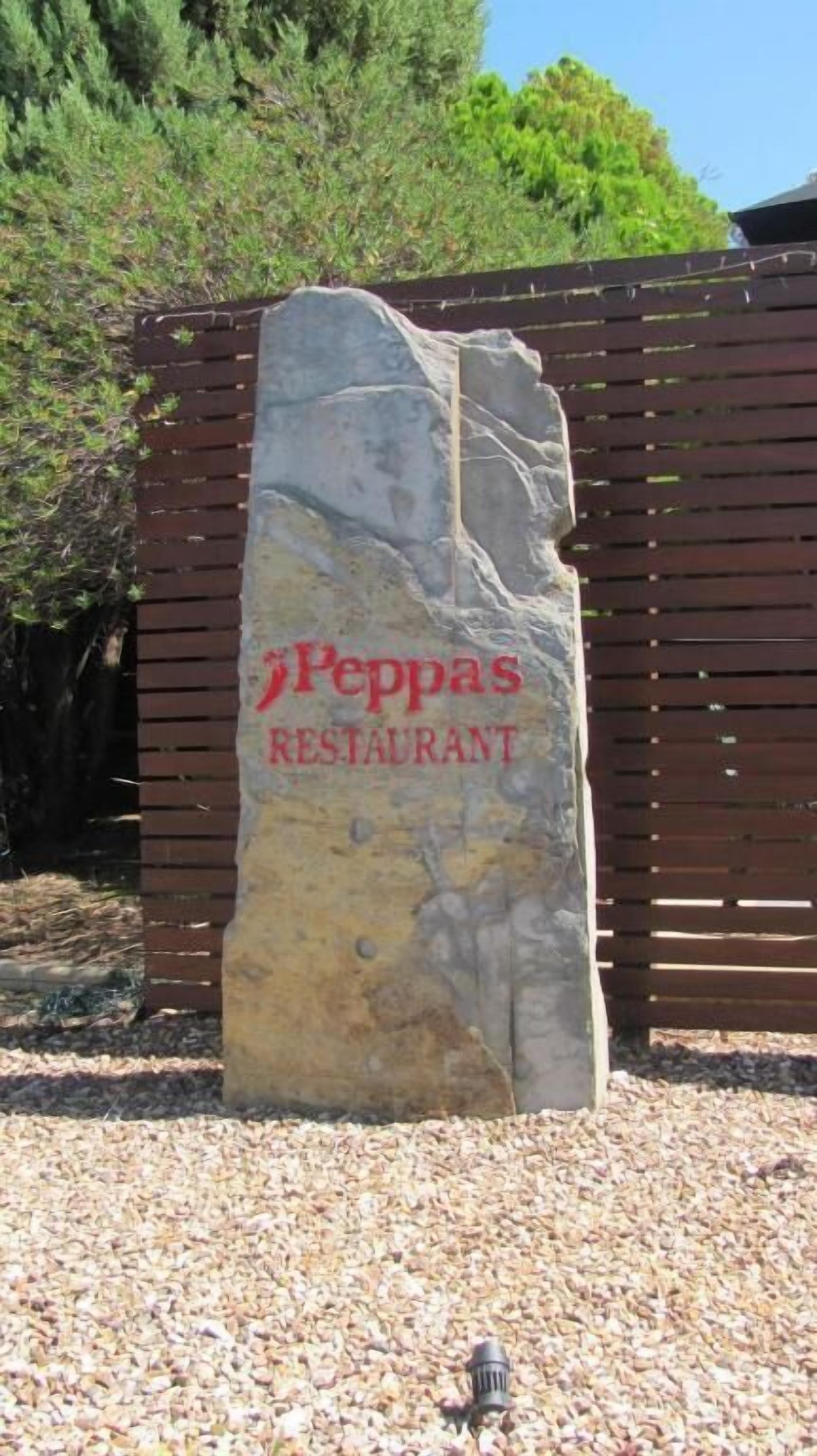 Un letrero de piedra grande con el texto 'Peppas Restaurant' en letras rojas.