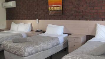 Una habitación de hotel con dos camas individuales, una pared de ladrillo, un cuadro y un teléfono en la mesita de noche.