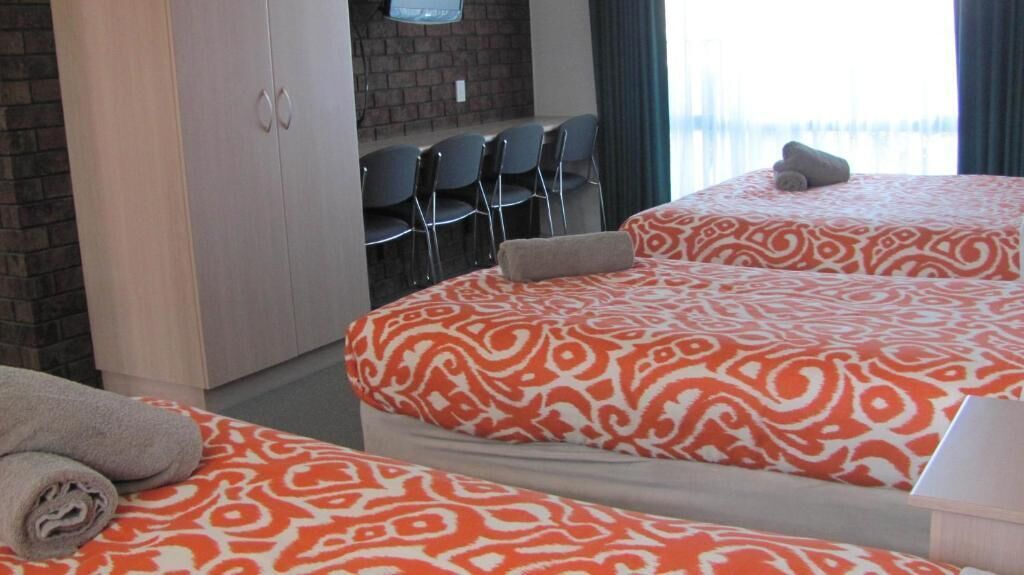 A hotel room with two beds, a desk, and chairs.