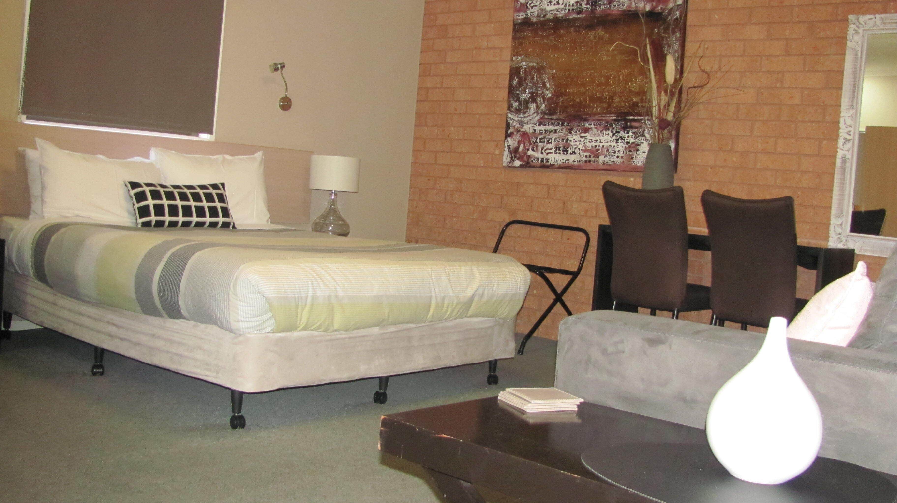 Een hotelkamer met een bed, een stoel, een tafel en een spiegel.