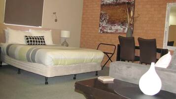 Een hotelkamer met een bed, een stoel, een tafel en een spiegel.