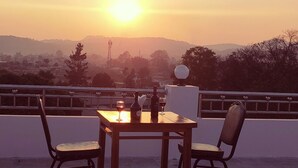 Une table avec deux chaises sur une terrasse offrant une vue sur le coucher de soleil.