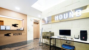 A reception area with a wooden desk, a computer, a chair, and a sign that reads "HOUND".