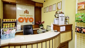 A hotel reception desk with a sign reading "Hotel Umimas OYO", a computer, a printer, and a basket of snacks. - OYO 89958 Hotel Umimas (Lahad Datu)