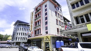 A multi-story building with a ground-level commercial space, a visible entrance, and several parked vehicles. - OYO 89958 Hotel Umimas (Lahad Datu)