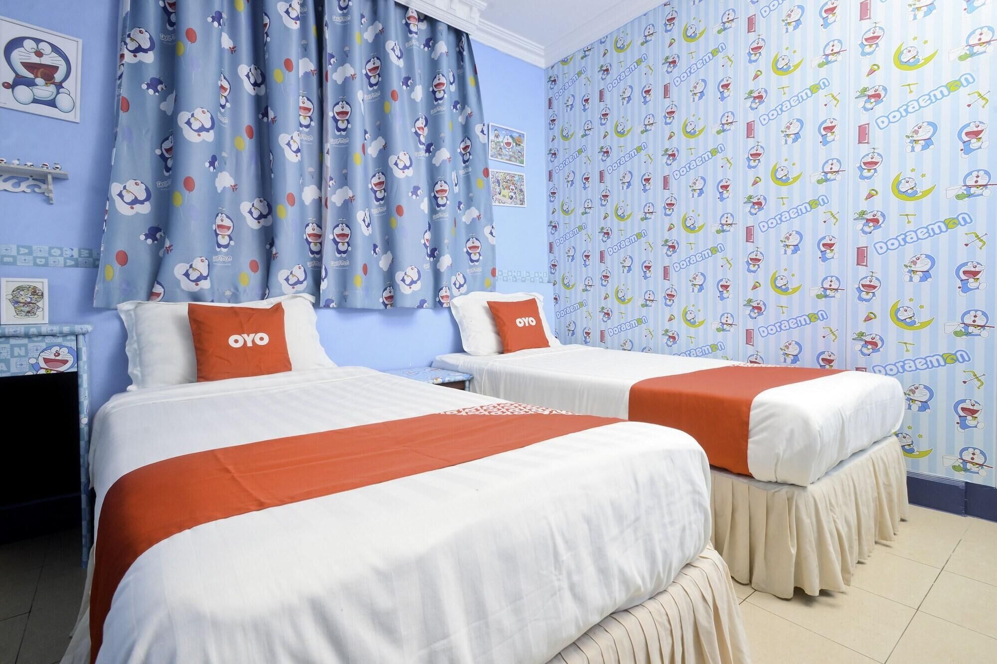 A hotel room with two beds, each with a white and orange bedspread, and a blue curtain with cartoon characters.