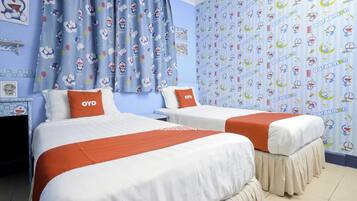 A hotel room with two beds, each with a white and orange bedspread, and a blue curtain with cartoon characters.