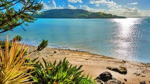 A beach with clear water, a sandy shore, and a distant green hill. - Yacht Club 19 Bijou De Mer 2 Buggies (Whitsundays)