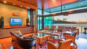A spacious living area with a large TV, comfortable seating, and a view of the water. - Yacht Club 19 Bijou De Mer 2 Buggies (Whitsundays)