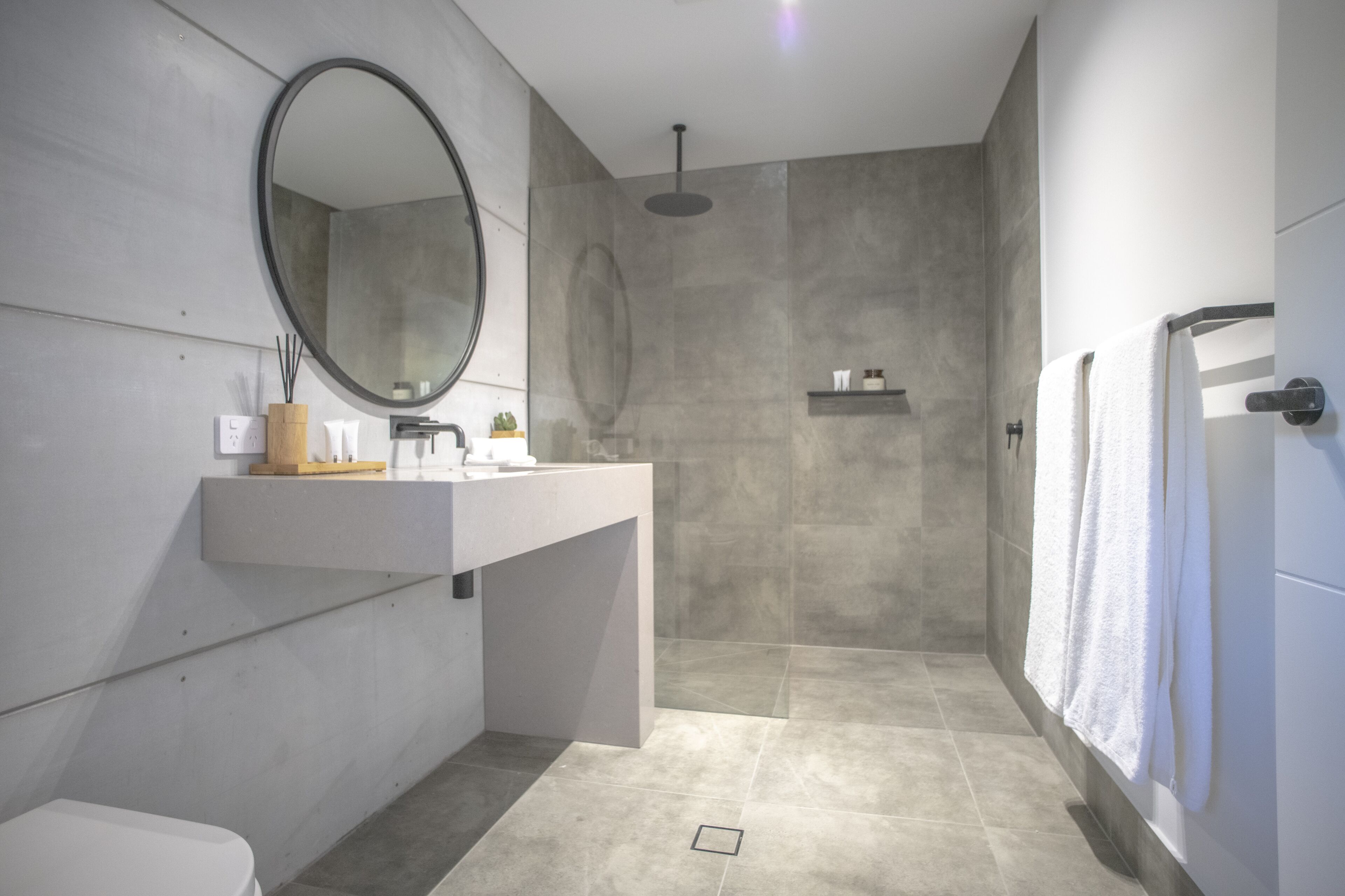 Een moderne badkamer met een grote spiegel, een douche en een toilet.